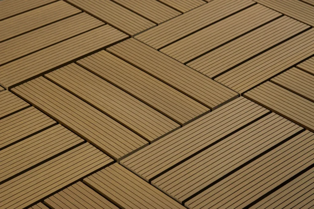 Close-up of interlocking wooden tiles arranged in a geometric, diagonal pattern. The tiles feature narrow, parallel slats, creating a modern and visually appealing design.