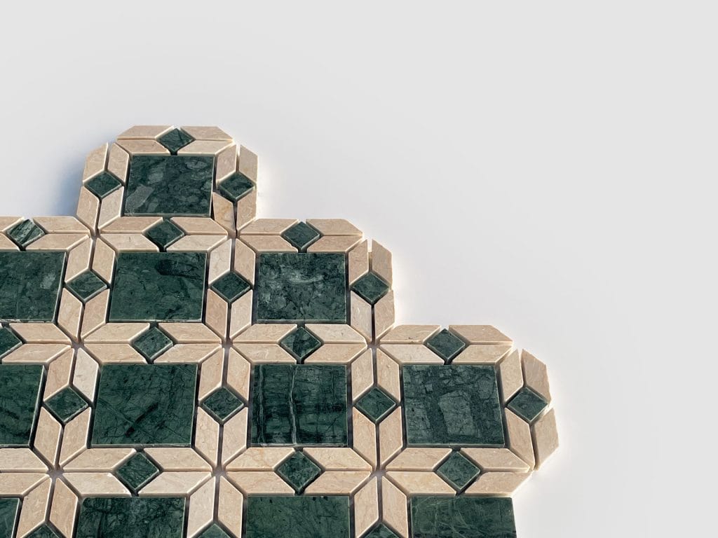Geometric tile pattern with dark green marble squares framed by beige diamond and rectangular shapes, arranged against a plain white background. The tiles form a partial, stepped design on the left side of the image.