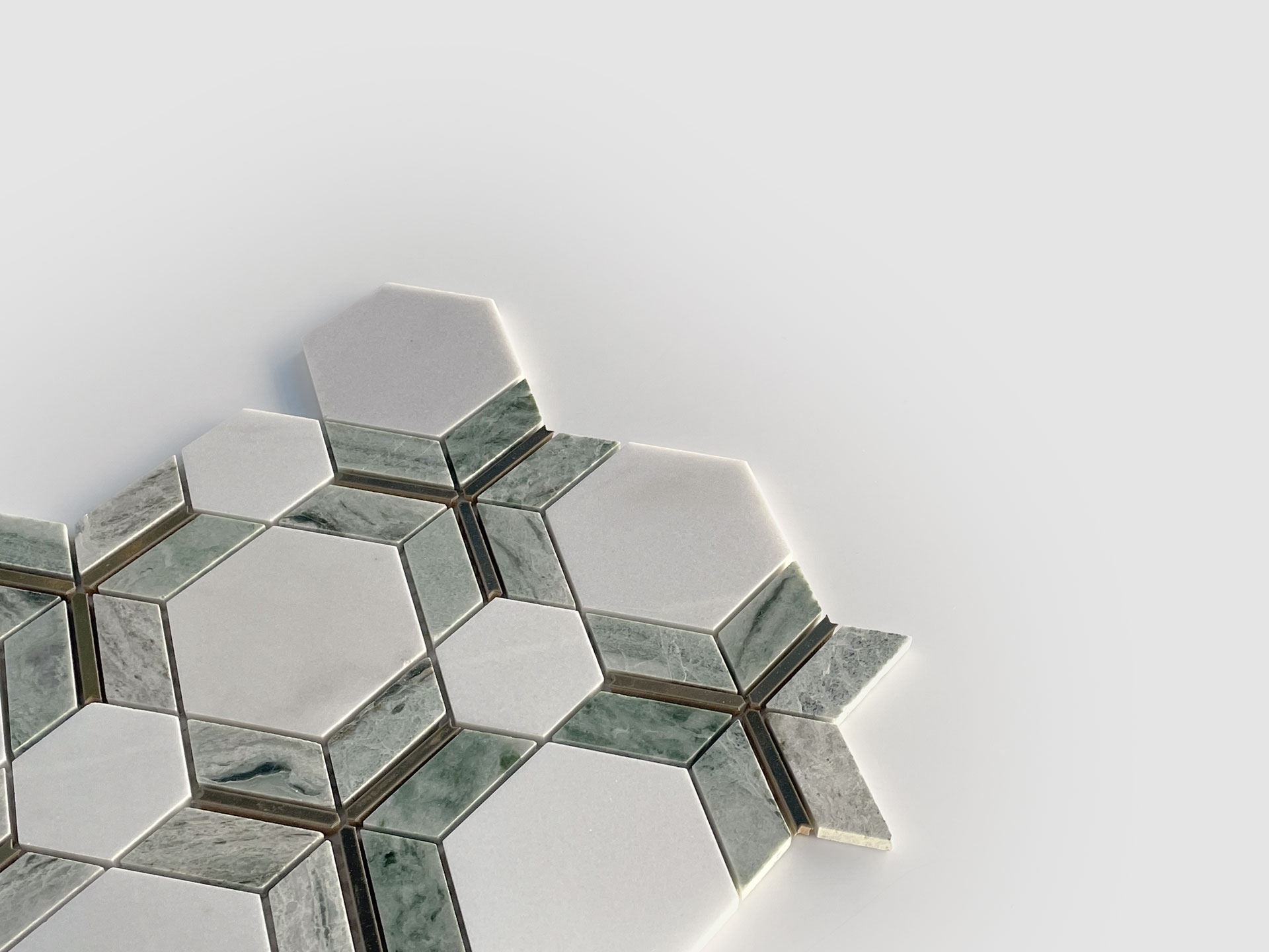 A geometric arrangement of hexagonal and rectangular tiles in white and greenish-gray tones, displayed on a light gray background. The pattern creates a visually striking, modern mosaic effect.