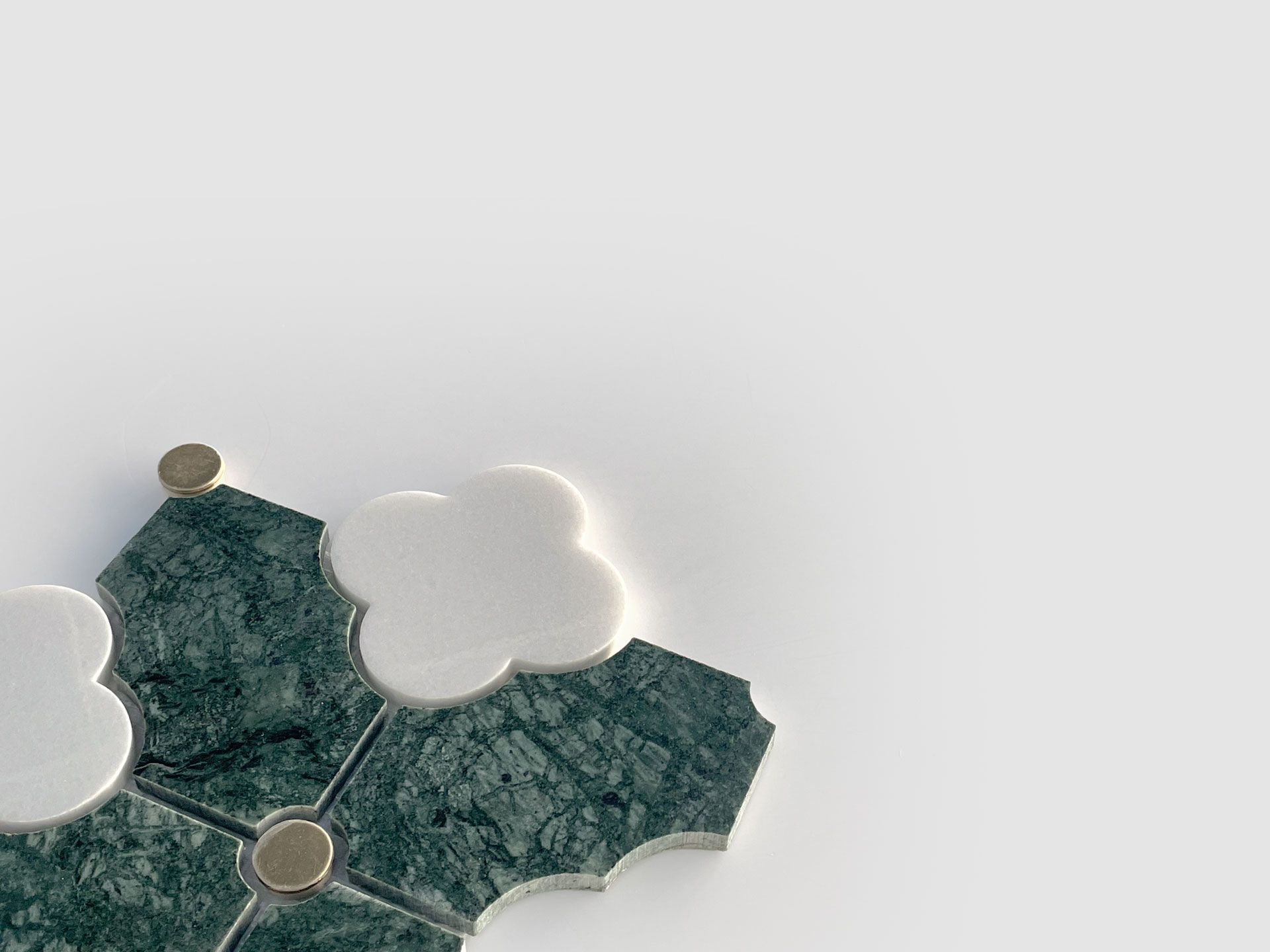 A geometric arrangement of green marble tiles and white clover-shaped tiles with small round gold accents, set against a plain light gray background.