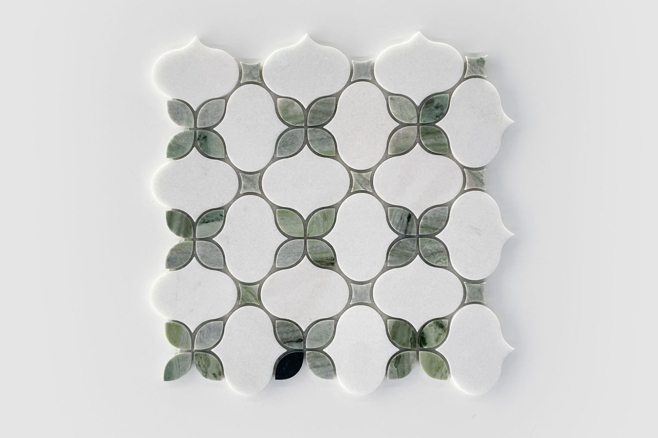 A square tile sheet featuring a geometric pattern of white shapes bordered by smaller, green leaf-like tiles on a light gray background. The design creates a repeating, symmetrical motif.