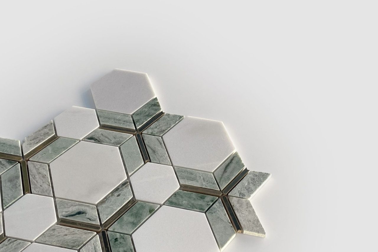 A geometric arrangement of hexagonal and rectangular tiles in white and greenish-gray tones, displayed on a light gray background. The pattern creates a visually striking, modern mosaic effect.