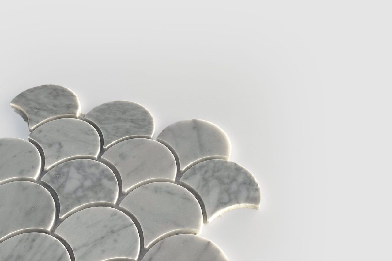 Several light gray, marble-patterned tiles shaped like scallop shells are arranged closely together on a plain, light background, forming a partial pattern with empty space around them.