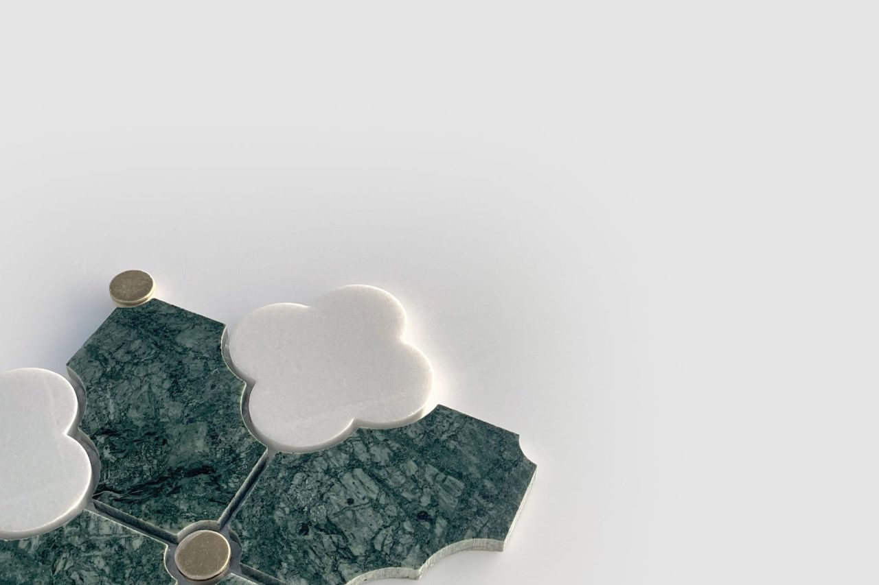 A geometric arrangement of green marble tiles and white clover-shaped tiles with small round gold accents, set against a plain light gray background.